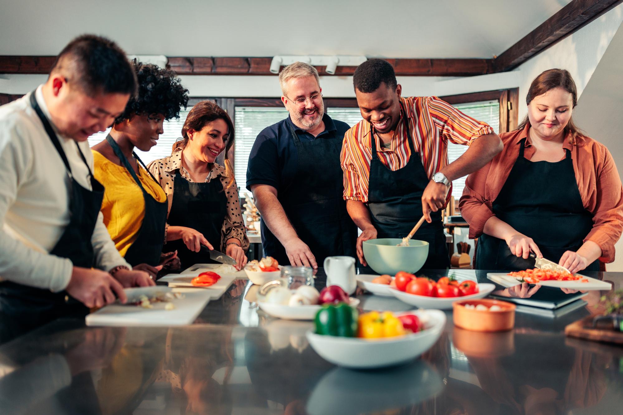 Large editorial photo: chef teaching a class around a long table